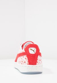 Punttia punaiset ja valkoiset urheilukengät, joissa on teksturoitu mokkanahkaselkä, Hello Kitty -kuvio, kultainen Puma-logo ja täplikkäät pohjat.