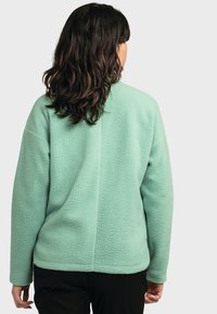 Mintgrüne Fleecejacke mit strukturiertem Obermaterial, langen Ärmeln und hohem Kragen. Verfügt über einen einfachen, lockeren Schnitt mit einer geraden Rückennaht.