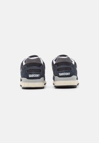 Temno plave suede i mrežaste tenisice s kremastim gumiranim potplatima, s podstavljenim ovratnikom i istaknutim natpisom "SAUCONY" na peti.