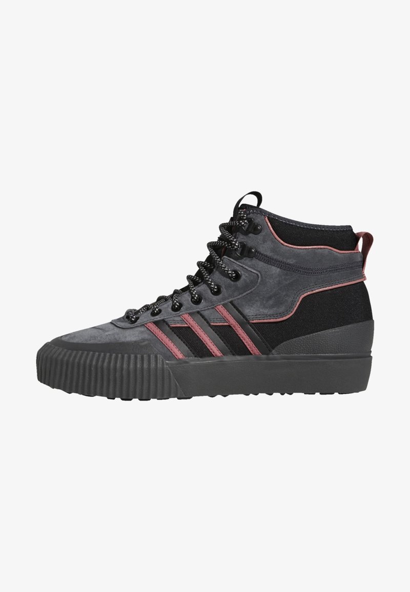 Deportivas de caña alta en ante negro y gris con acentos rojos. Presentan una suela de goma texturizada y cordones en la parte delantera con ojales de metal.