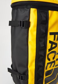 Zaino nero e giallo con finitura testurizzata, grande logo, spallacci regolabili e parte superiore con zip per una chiusura sicura.