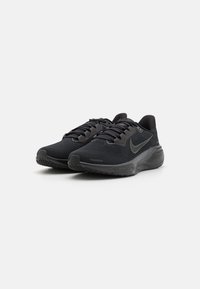 Schwarze Sportschuhe aus atmungsaktivem Mesh und Gummi. Merkmale sind ein strukturiertes Obermaterial, ein gepolsterter Schaft und ein auffälliges Swoosh-Logo an der Seite.