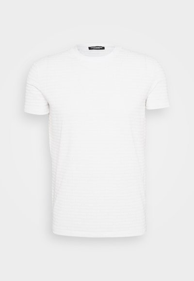 Hvit kortermet t-skjorte med rund hals og subtil, preget gjentatt merkevaretekstur, presentert på en enkel lys grå bakgrunn.