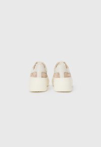 Beige lærersneakers med plattformsåle, med semskede detaljer og utskjæringer ved hælen. Subtilt logo preget bakpå.