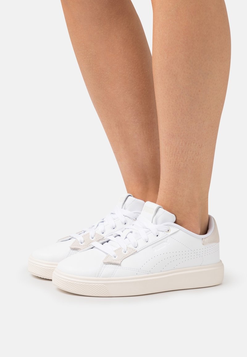 Vita sneakers i slät läder, med beige accenter, perforerade detaljer, platta snören och en texturerad gummisula.