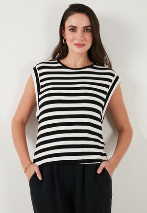 T-shirt à manches courtes rayé noir et blanc avec un col rond et une coupe décontractée. Il présente une texture lisse et des fentes sur les côtés à l'ourlet.
