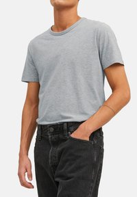 Grijze katoenen T-shirt met een ronde hals, korte mouwen en een losse fit, gecombineerd met zwarte denim jeans. Voorzien van een soepele textuur en een eenvoudig ontwerp.