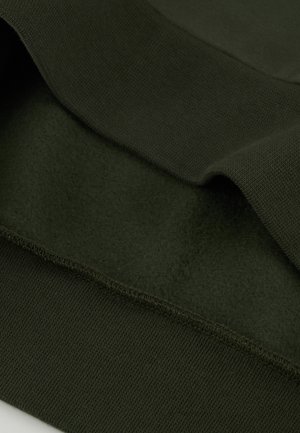 Donkergroen fleecestof met een gladde textuur, met een geribde tailleband en zoom voor een comfortabele pasvorm. Gelaagde uitstraling benadrukt de zachtheid.