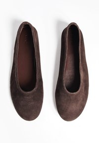 Des ballerines en daim marron avec un bout arrondi et une doublure intérieure lisse. Les chaussures présentent un design simple et sans couture, sans matériel visible.