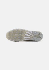 Semelle de chaussure de sport blanche avec une semelle en caoutchouc à motif, présentant un design lisse et incurvé avec des accents en gris clair et des tons plus clairs.