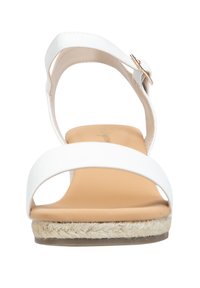 Sandale blanche avec de larges brides à l'avant, une bride à l'arrière avec une boucle, et une semelle intérieure texturée couleur beige avec une semelle en style espadrille tressée.