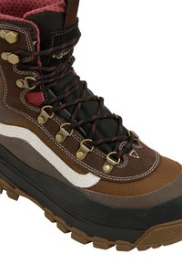 Scarpa da trekking marrone e nera con colletto imbottito con accenti rossi, occhielli in metallo, lacci neri e rossi, striscia bianca laterale e suola robusta.