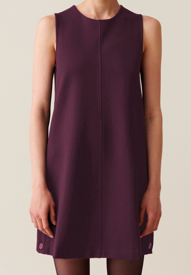 Robe sans manches bordeaux avec un col rond, texture lisse, coupe droite et un petit accent circulaire près de l'ourlet.