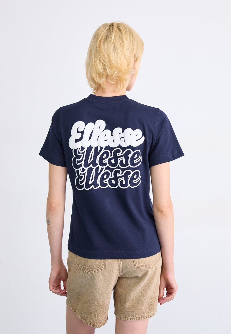 T-shirt bleu marine avec un grand logo blanc "Ellesse" au dos. Manches courtes, col rond, fabriqué en coton avec une texture lisse.