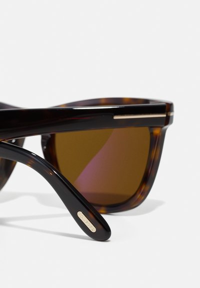 Ochelari de soare tip scoică cu lentile maro. Mânere mate, accent de aur pe tâmple și un design curbat pentru un aspect modern.