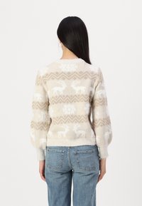 Maglione crema con lavorazione a maglia testurizzata, caratterizzato da un motivo geometrico, renne bianche e fiocchi di neve; orlo e polsini a costine, vestibilità comoda.