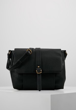 Mustalainen nahkainen viestintälaukun, jossa on läppä suljettuna, kultasävyiset yksityiskohdat, säädettävä hihna ja sileä pinta. Sisältää pystysaumadetaileja.