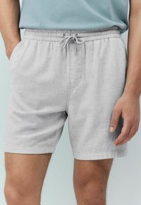 Light gray shorts in a textured fabric, featuring an elastic waistband with a drawstring, side pockets, and a relaxed fit design.