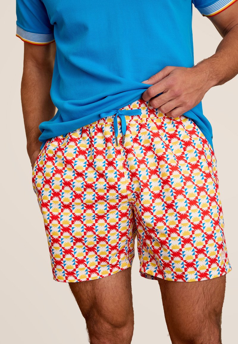 Zwemshorts met een kleurrijk geometrisch patroon in rood, geel, blauw en wit. Elastische tailleband met trekkoord, lichtgewicht stof.
