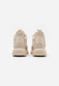 Vaaleat lenkkarit, joissa on paksu pohja, verkko- ja mokkanahkapinta, varustettu valkoisella "BUFFALO" -brändäyksellä takana ja vetonauhoilla.