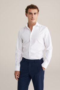 Witte langmouwenshirt met een klassieke kraag en knopen, gecombineerd met marineblauwe tailored broek. Soepele stofstructuur, slim fit ontwerp.