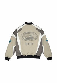 Veste de course beige et grise avec col et poignets noirs, arborant l'inscription « PROHIBITED Racing Club BERLIN » et un graphisme de voiture dans le dos.