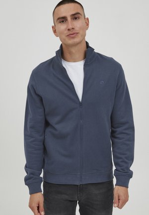 Sudadera navy con cremallera en mezcla de algodón, que presenta un cuello alto, puños acanalados y un pequeño logo en el pecho. Textura suave y corte relajado.