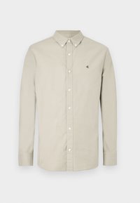 Camicia beige chiaro con bottoni, maniche lunghe, colletto e logo CK ricamato sul petto. Tessuto liscio con un design classico.