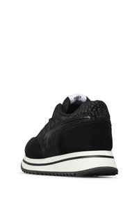 Scarpa sportiva nera con tomaia in maglia texturizzata, dettagli in suede e suola in gomma bianca con strisce nere. Il design comprende un dettaglio del logo nell'angolo.