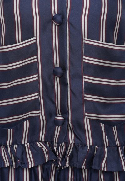 Abito senza maniche blu navy con strisce verticali bianche e marrone borgogna, dotato di due tasche frontali, tre bottoni e orlo arricciato.