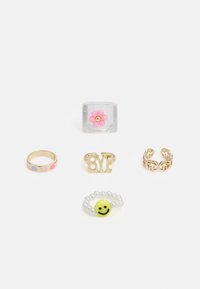 Cinco anéis exibidos: um anel de flor transparente, um anel dourado com a palavra "BYE", um anel dourado com pontos coloridos, um anel de filigrana dourada e um anel de contas com um sorriso.