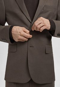 Brauner karierter Anzugsakko mit tailliertem Schnitt. Verfügt über Revers mit Kerb, zwei Fronttaschen und Knöpfe an den Manschetten. Strukturierter Stoff.