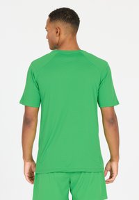 Groene sport T-shirt met korte mouwen, lichtgewicht, textuurstof, ronde hals en platte naden, gedragen met bijpassende shorts.