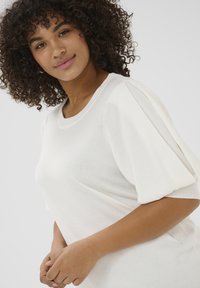 White knit top featuring puff sleeves and a round neckline. Soft texture with smooth finish, designed for comfort and ease of wear.