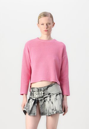 Rosa ribbad stickad tröja med en kort design; kombinerad med en grå denimminikjol med plisserad stil och spännelement.