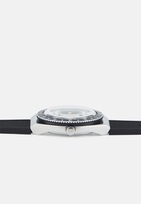 Round watch features a stainless steel case, black rubber strap, clear domed glass, and a black rotating bezel with white numerals.