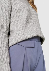 Pull en tricot côtelé gris clair avec un ourlet court associé à un pantalon bleu sur mesure doté de poches latérales et d'une coupe plate.