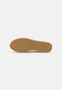Semelle de chaussure plate beige avec semelle en caoutchouc affichant la taille 37, semelle avant lisse et section de talon nervurée sur fond blanc.
