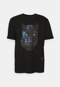 Camiseta negra de manga corta con una gran cara realista de un pantera negra impresa en el frontal y un pequeño texto rojo cerca del dobladillo inferior.