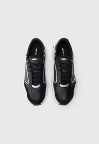 Sapatilhas de couro preto com painéis em malha, detalhes em prata e solas brancas. Apresentam atacadores redondos e uma marca distinta na lingueta.