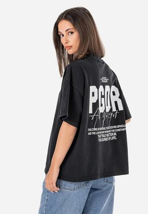 Juoda didelė t-shirt su balta grafine užrašu ant nugaros. Trumpomis rankovėmis, apvaliu kaklu, pagaminta iš medvilnės, pasižymi laisvu siluetu.