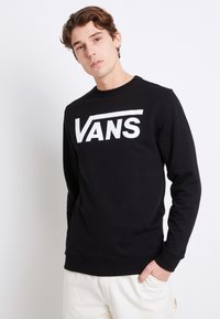 Czarny sweter z okrągłym dekoltem wykonany z mieszanki bawełny, z dużym białym logo "VANS" na piersiach. Ściągacze przy mankietach i u dołu.