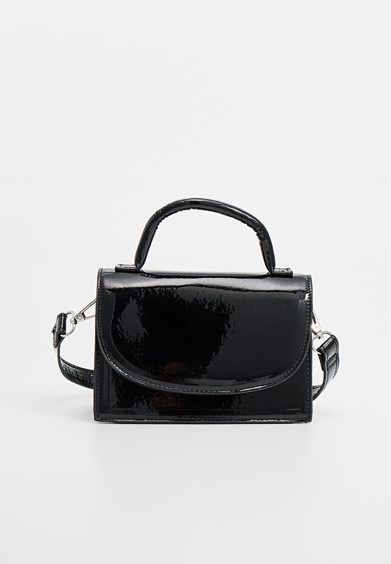 Sac à main en cuir verni noir avec un rabat arrondi, une poignée supérieure, une bandoulière réglable et une texture lisse et brillante.