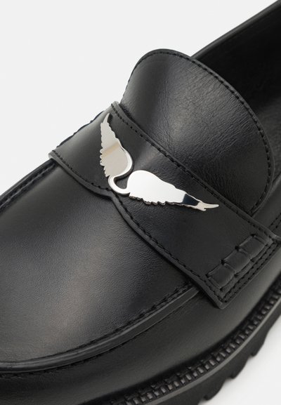 Melni ādas loafers ar gludu faktūru, ar sudraba spārnu emblemu uz siksnas un detalizētu šuvumu gar zoli.