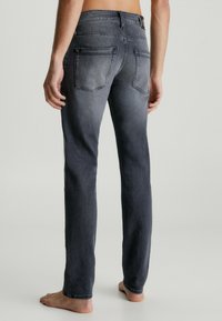 Grå denimjeans med rak ben-design, med subtila blekningar, två bakfickor och en synlig etikett på midjan.