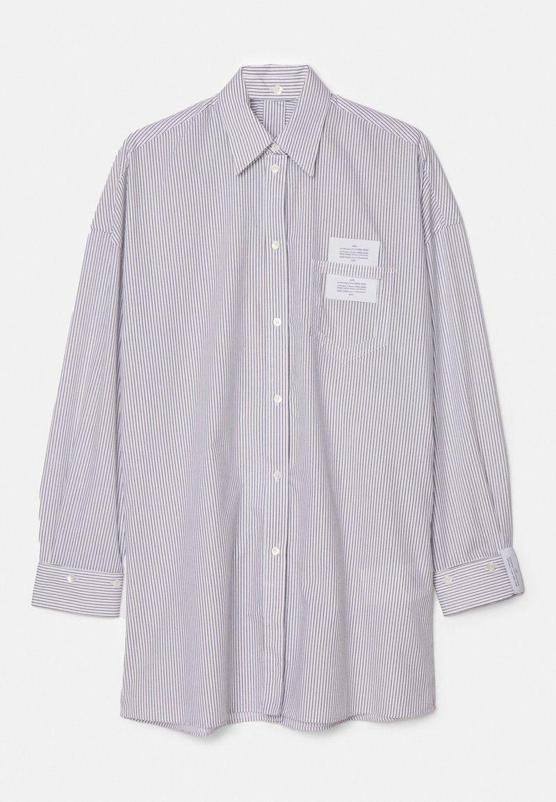 Chemise à rayures à manches longues en blanc et marine, avec un col, une fermeture à bouton et deux poches poitrine avec étiquettes. Texture douce.
