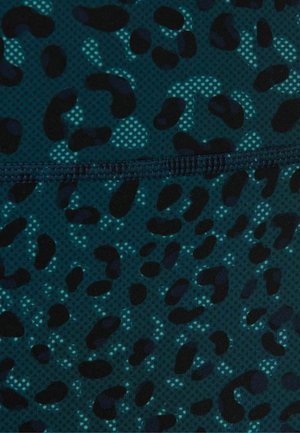 Donker turquoise stof met zwarte en lichtblauwe onregelmatige luipaardvlekken en zichtbare horizontale stiksels over het midden.