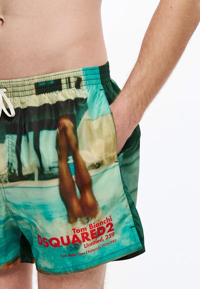 Badeshorts mit einem farbenfrohen, fotografischen Druck von Beinen in einem Pool, mit grünen Seiten und einem weißen Kordelzug am Bund. Enthält rotes Markenlogo.