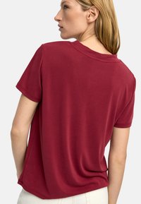 Czerwona bawełniana koszulka z luźnym krojem, krótkimi rękawami i okrągłym dekoltem. Posiada gładką fakturę i prosty dół z tyłu.