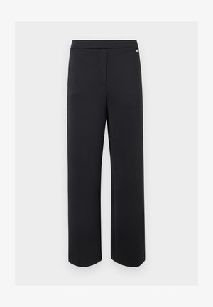 Pantalon noir droit avec une fermeture frontale dissimulée et un petit logo métallique près de la ceinture sur fond blanc.